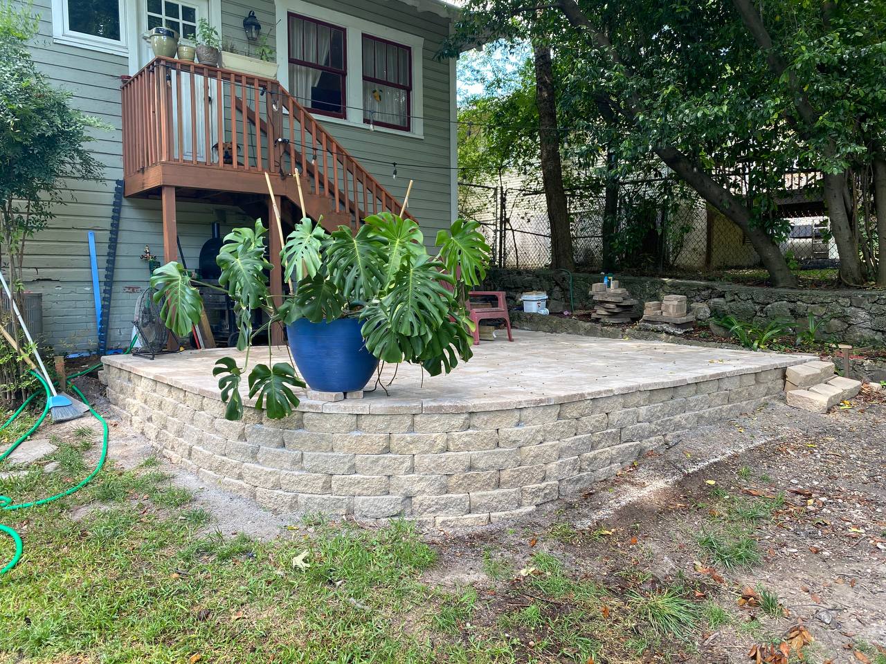 Final completed stone paver patio with a large Monstera plant